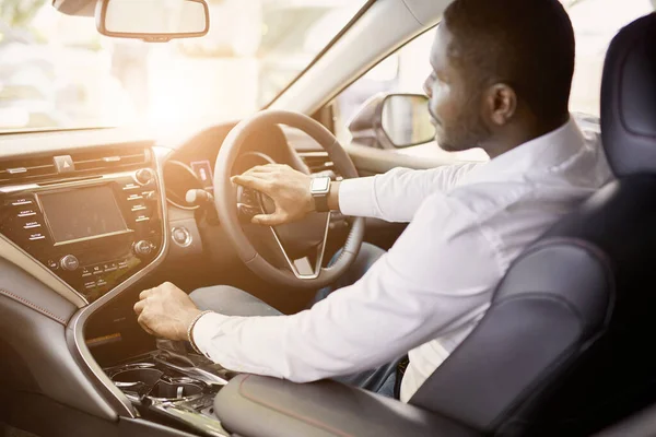 Afro man sits inside of new automobile in dealership — Stock Photo, Image