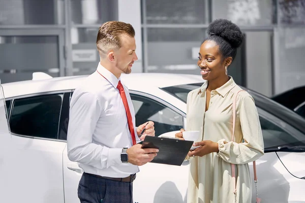 Çekici Afrikalı bayan bir fincan çay içip satış temsilcisini dinliyor.