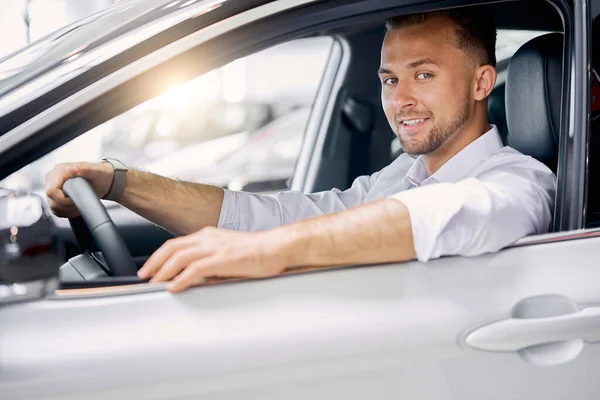 Portrait of handsome caucasian guy sitting behind the wheel of new car — Stock Photo, Image