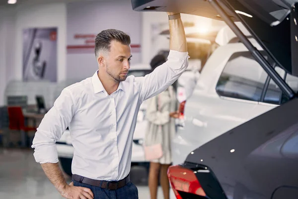 Schöner kaukasischer Geschäftsmann untersucht ein Auto, bevor er es kauft — Stockfoto