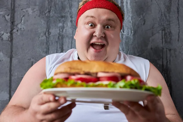 Przystojny biały tłuszcz człowiek będzie jeść Duży smaczny kanapka — Zdjęcie stockowe