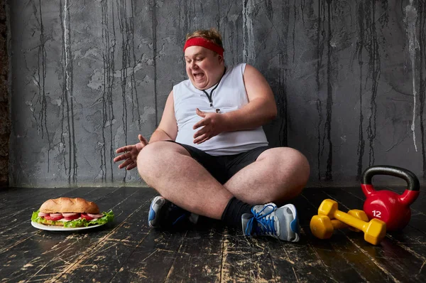 Tłuszcz człowiek będzie jeść Duży kanapka pomimo niedawnego treningu sportowego — Zdjęcie stockowe