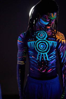 Göğsünde ve vücudunun diğer kısımlarında floresan izleri olan yakışıklı Afrikalı bir adam.