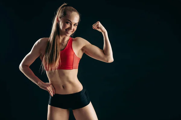 Menina ajuste alegre está mostrando seu bíceps — Fotografia de Stock