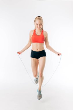 Güzel, sarışın, zayıf kız atlayan ipin üzerinden atlıyor.