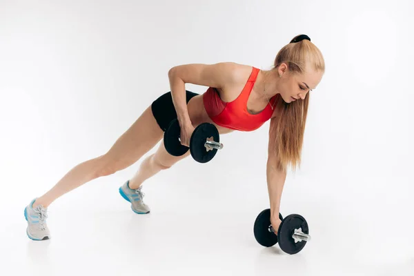 Mujer joven con mancuernas haciendo un ejercicio de fitness push up . — Foto de Stock