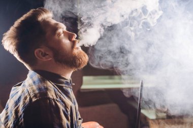 Sihirli sigara içmek. Genç adam nargileyle rahatlıyor.
