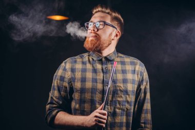 Kızıl saçlı vahşi adam sigara içmekten zevk alıyor.