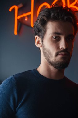 İyi görünümlü, zayıf, siyah kısa dalgalı saçlı ve kameraya poz veren bir adam.