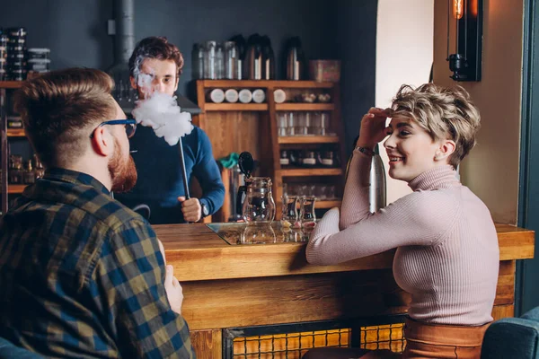 Jovens homens e mulheres alegres conversando na mesa de bar — Fotografia de Stock