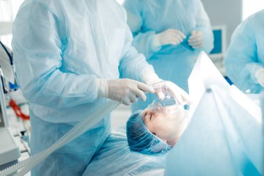 Hasta adam burnundan nefes almakta zorlanıyor, bu yüzden doktorlar ona maske takıyor.