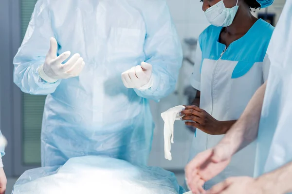 Beautiful african doctor puts on medical gloves — Stock Photo, Image