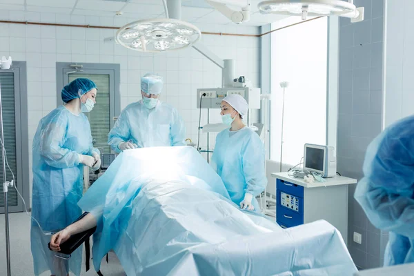 Equipo de cirujanos trabajando con el paciente en el quirófano de luz — Foto de Stock