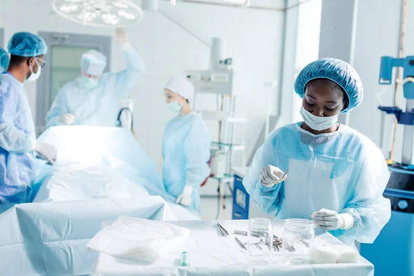 Enfermera alegre de buen aspecto con instrumento médico esteralizado — Foto de Stock