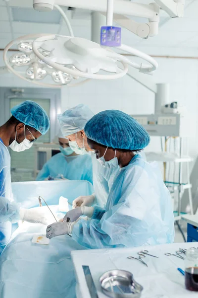 Talentosos médicos de raza mixta utilizando un láser para realizar una cirugía delicada — Foto de Stock