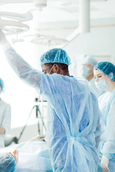 Afro läkare i mask justeringslampa i operationssalen på sjukhuset — Stockfoto