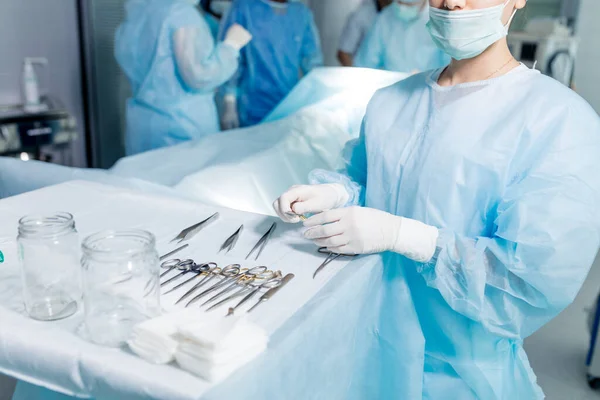 Ung läkare står nära bordet full av olika instrument — Stockfoto