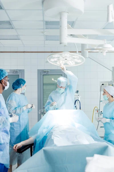 Atrakcyjny lekarz regulujący oświetlenie sali operacyjnej — Zdjęcie stockowe
