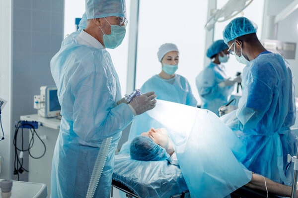 male patient lying on an operating table with surgeons in a surgery room