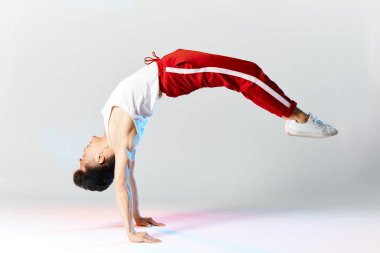 Asya Bboy dondurucu dublörde baş aşağı duruyor havada bacaklarla dengede duruyor.