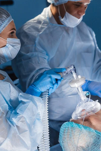 Lääketieteellinen tiimi suorittaa kirurgisen operaation kirkkaassa modernissa leikkaussalissa — kuvapankkivalokuva