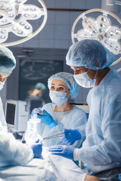 Diverse team van chirurgen, assistenten en verpleegkundigen die invasieve chirurgie — Stockfoto