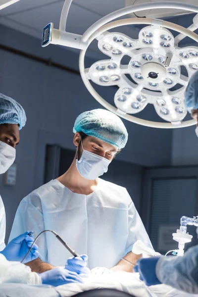 Young doctor, surgeon wearing medical protective mask in operating room