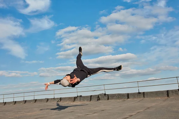 Bailarín de la calle hipster chico hace la vuelta con el brazo de apoyo en el techo al aire libre. —  Fotos de Stock