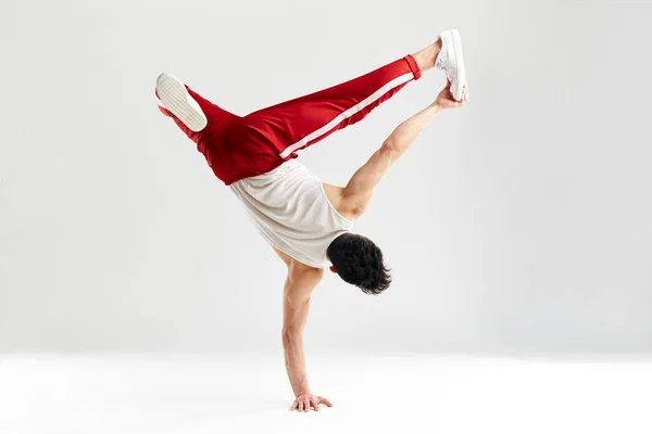 Moderne danser staat aan de ene kant bevriezen met uitgesplitste handen in lucht op wit — Stockfoto