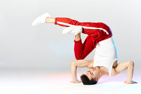 asian b-boy exercising in break dance on white background doing shoulder freeze