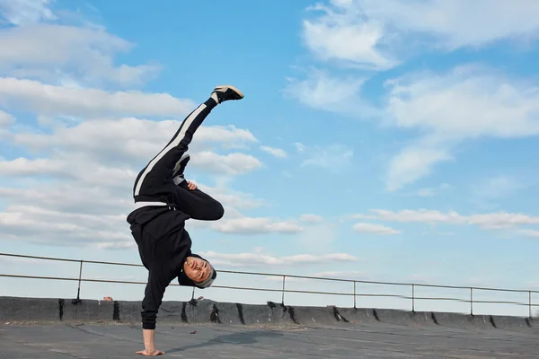 Coreano estilo urbano masculino dançarino realizando breakdance suporte no topo telhado — Fotografia de Stock