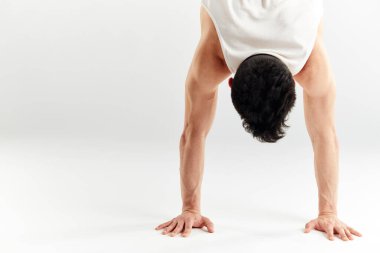 Kırmızı eşofmanlı genç adam beyaz arka planda amuda kalkıyor.