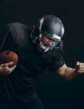 Amerikan futbolu sporcusu siyah stüdyo duvarından izole edildi.
