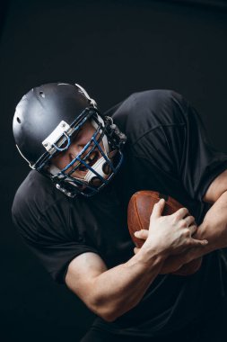 Amerikan futbolu sporcusu siyah stüdyo duvarından izole edildi.