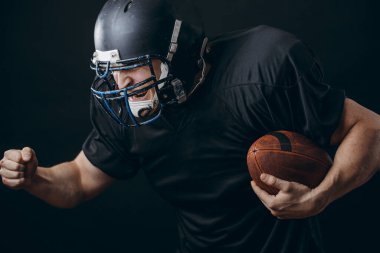 Amerikan futbolu sporcusu siyah stüdyo duvarından izole edildi.