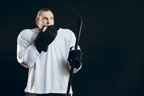 Guapo joven sosteniendo palo de hockey cubre la boca con la mano expresa miedo —  Fotos de Stock