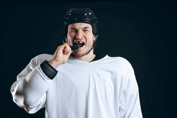 Jugador de hockey muerde el disco con los dientes rotos y mirando a la cámara con una sonrisa. —  Fotos de Stock