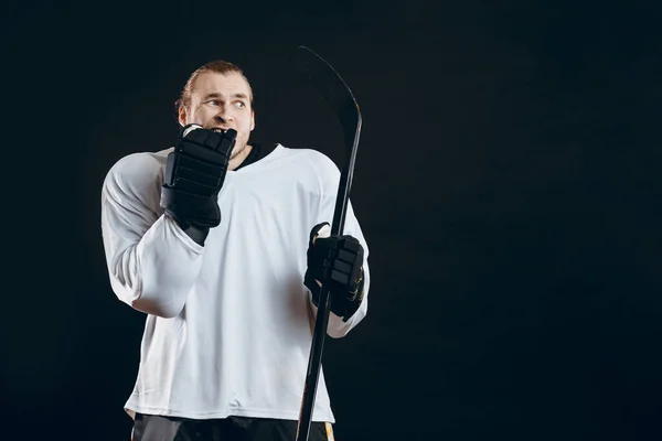 Snygg ung man som håller hockeyklubba täcker munnen med handen uttrycker rädsla — Stockfoto
