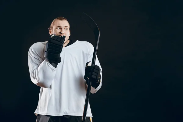 Guapo joven sosteniendo palo de hockey cubre la boca con la mano expresa miedo —  Fotos de Stock