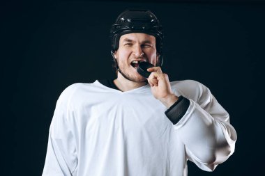 Hokey oyuncusu diski kırık dişleriyle ısırdı ve kameraya sırıtarak baktı..