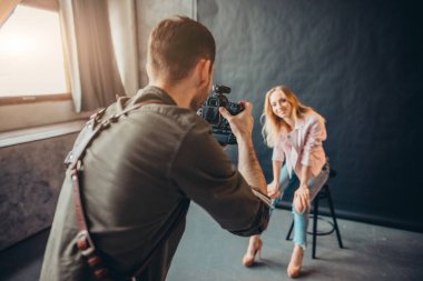 Genç aktif fotoğrafçı yeni modern kamerasını iş yerinde kullanıyor.