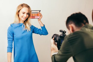 Genç fotoğrafçı bir kozmetologla çalışıyor.