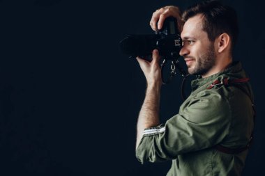 Dijital kamerayla fotoğraf çeken yakışıklı bir adamın yan görüntüsü..