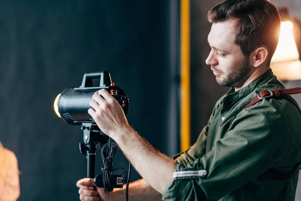 Young creative photographer controlling the light at the studio — Stock Photo, Image