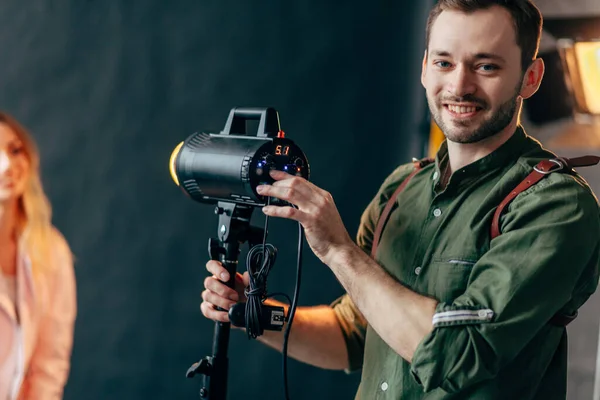 Flaş ekipmanlarının yanında duran mutlu fotoğrafçı.