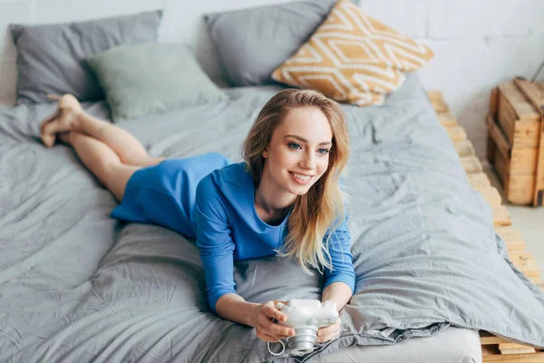 Feliz jovem mulher tendo um descanso na cama — Fotografia de Stock