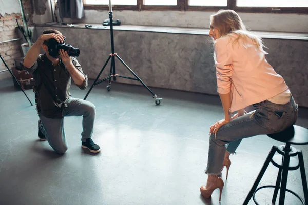 Joven fotógrafo ambicioso sentado en su rodilla y tratando de hacer la mejor foto — Foto de Stock