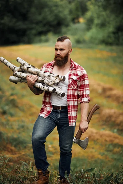 Bärtiger Mann mit Feuerholz und Axt an der Schulter — Stockfoto
