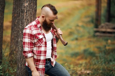 Sakallı oduncu ormanda baltayla dikiliyor.