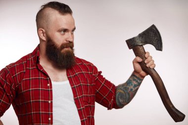 Sakallı erkek, elinde baltayla stüdyoda poz veriyor.